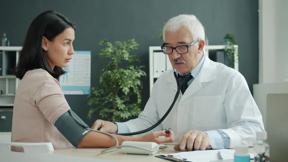 A doctor measuring a woman's blood pressure with an arm cuff during a consultation