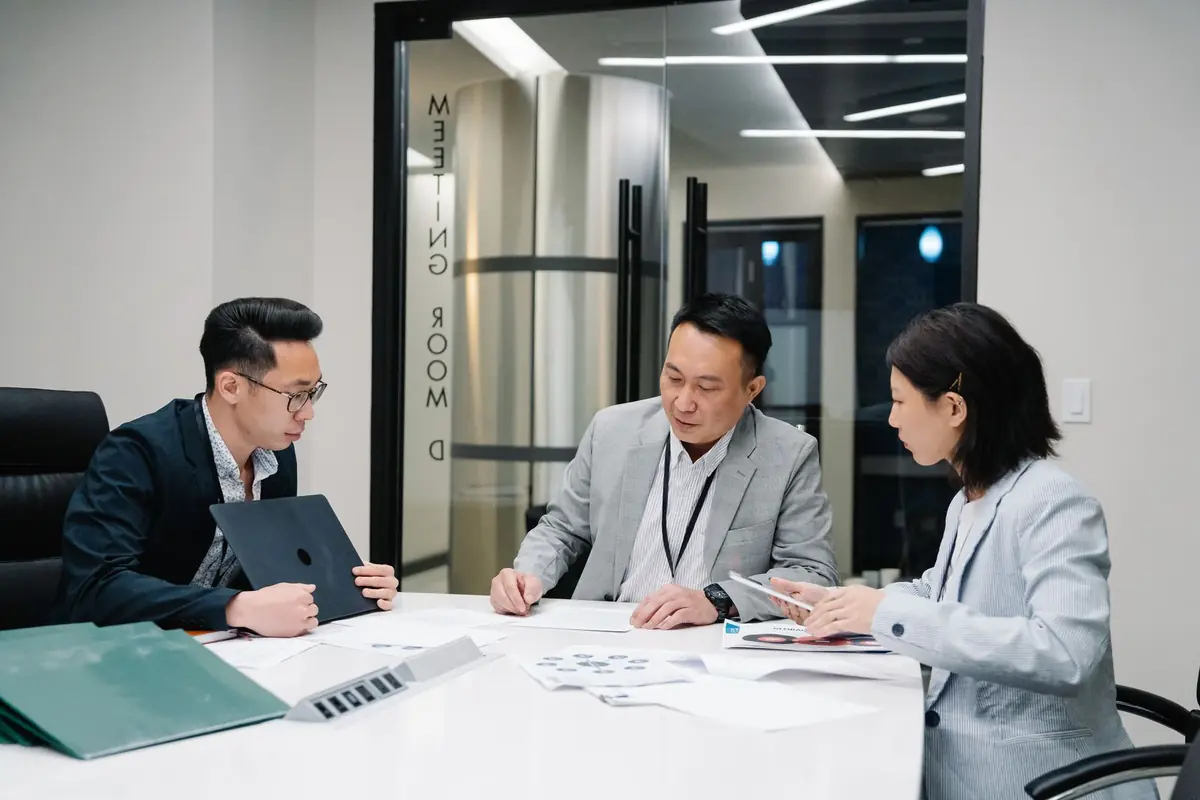 Three colleagues reviewing documents together at a meeting-room table