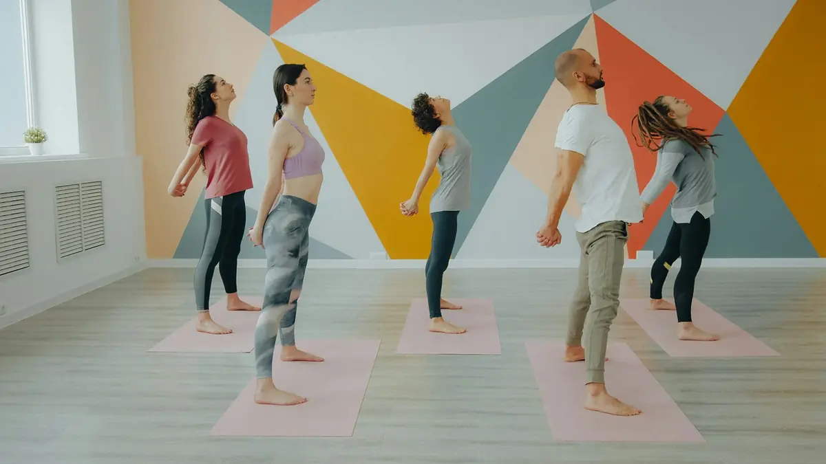 A small group of people stretching on mats in a bright studio