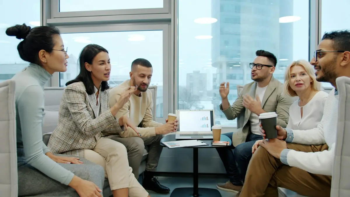 A group of colleagues talking together in a bright, modern office lounge