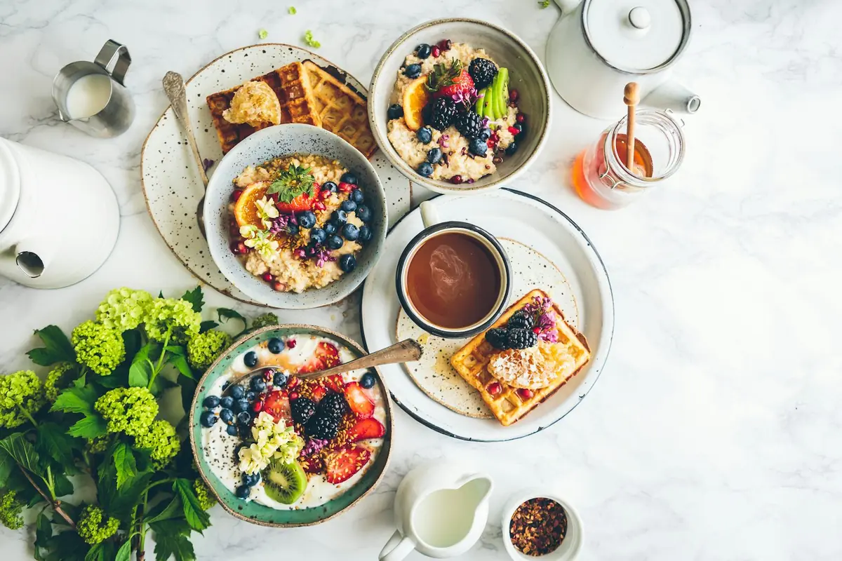 Overhead view of breakfast bowls with yoghurt, fruit and oats on a marble table