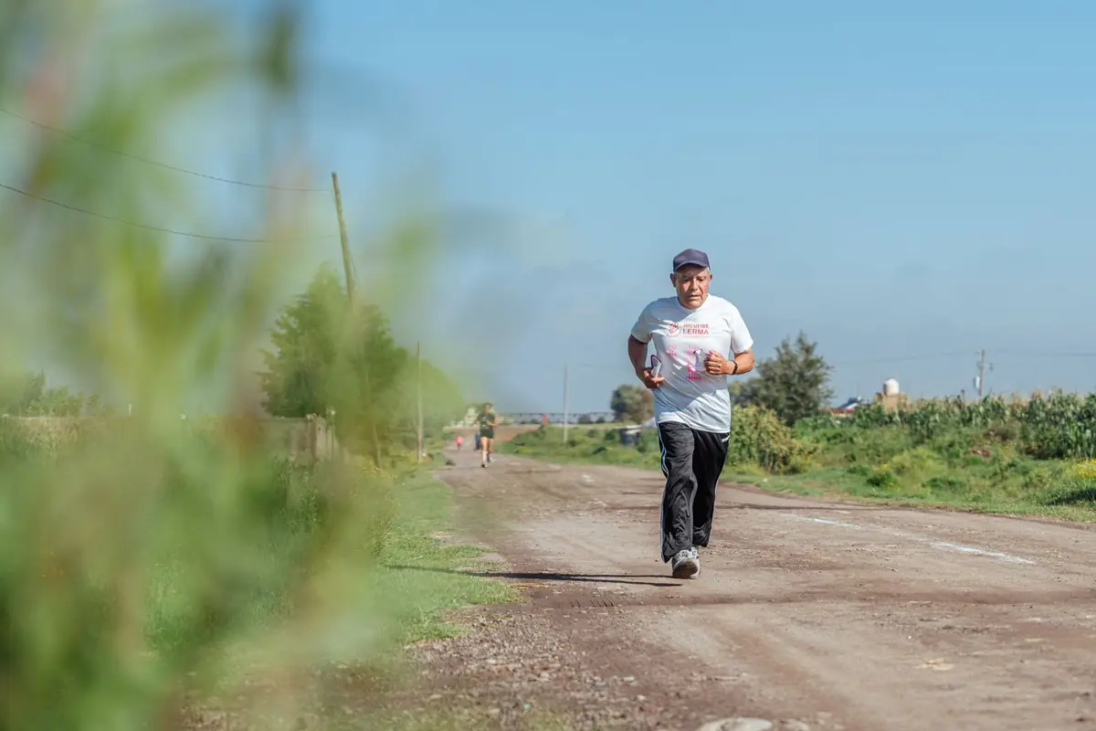An older man jogging along a dirt road in the countryside